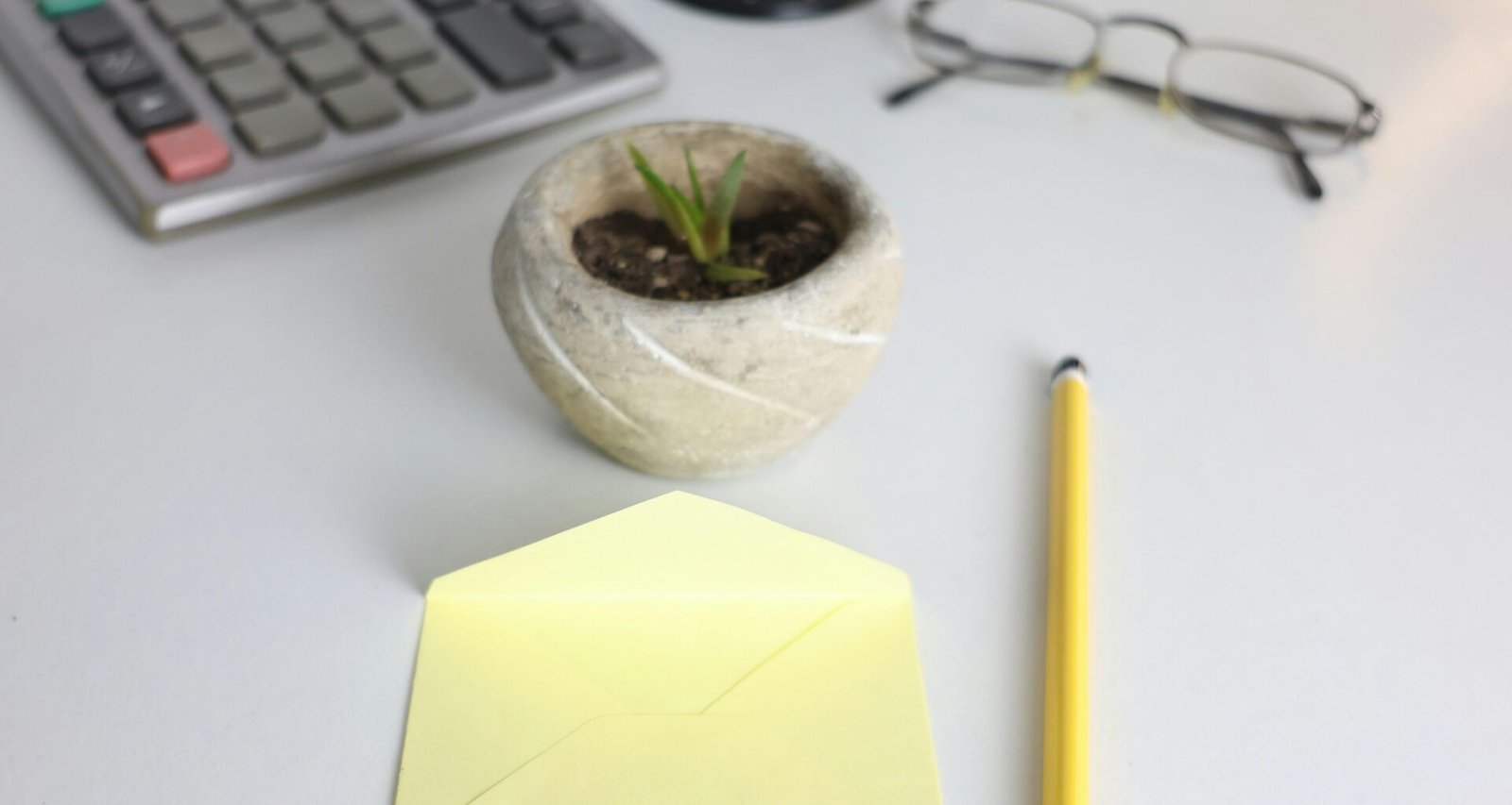 Schreibtisch mit Taschenrechner, Brille, kleiner Pflanze und Bleistift – modernes Arbeitsumfeld, ideal für Büro und Homeoffice