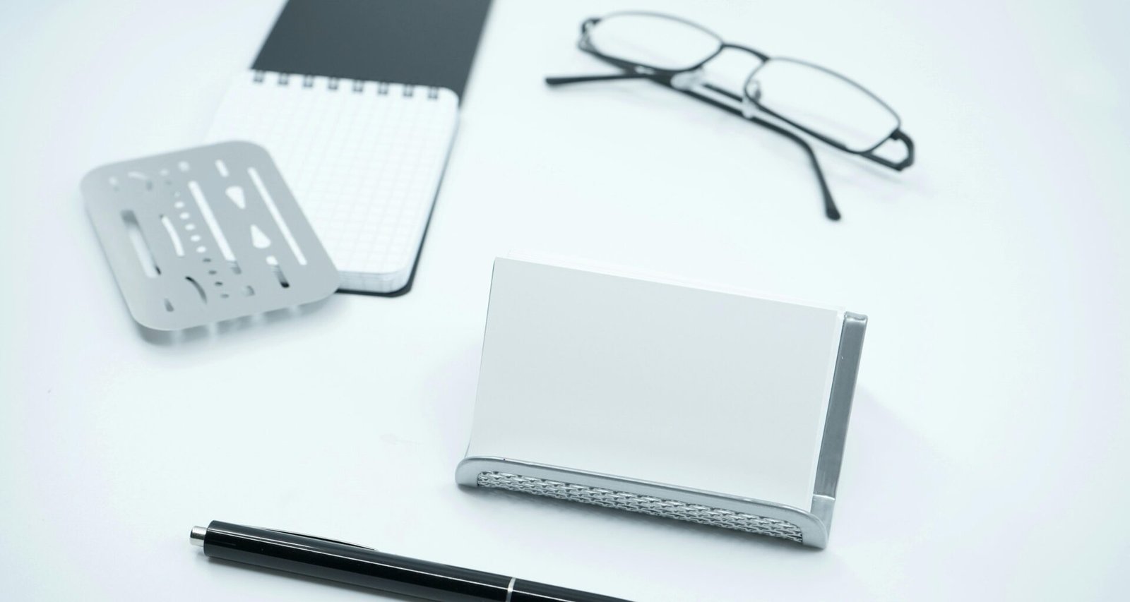 Schwarze Brille liegt neben weißem Druckerpapier und einem schwarzen Stift auf einem Schreibtisch, ideale Büroausstattung.