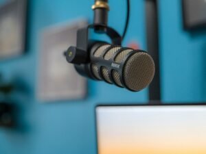 Schwarzes und silbernes Mikrofon steht auf einem schwarzen Stativ vor dunklem Hintergrund, ideal für Studioaufnahmen