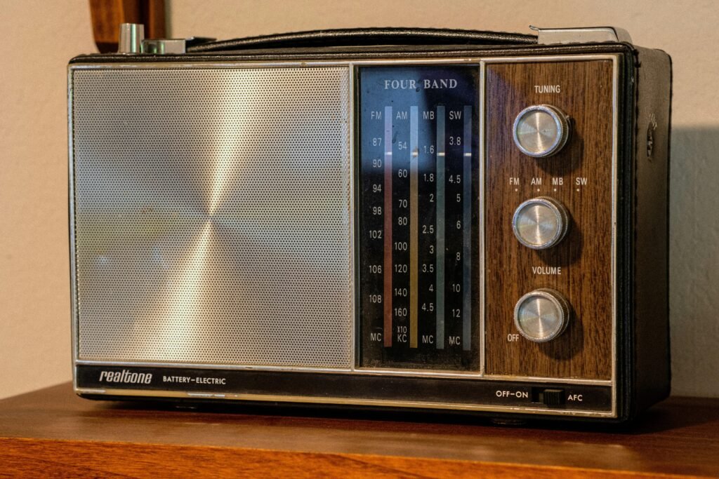 Schwarzes und silbernes Radio auf braunem Holztisch, Detailaufnahme eines klassischen Radiogeräts im Vintage-Stil