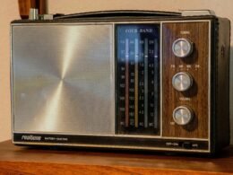 Schwarzes und silbernes Radio auf braunem Holztisch, Detailaufnahme eines klassischen Radiogeräts im Vintage-Stil