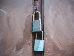 Schwarzes und silbernes Vorhängeschloss liegt auf weißem Kunststoff, Detailaufnahme zur Darstellung von Sicherheit