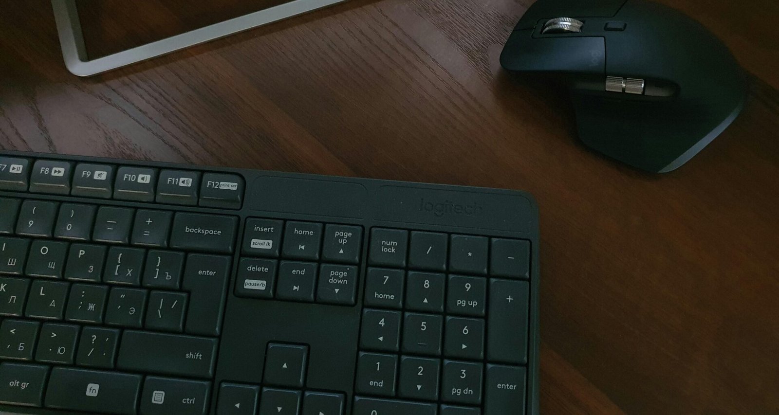 Schwarze Computertastatur neben einem weißen iPad auf einem Schreibtisch, geeignet für effizientes Arbeiten im Büroalltag