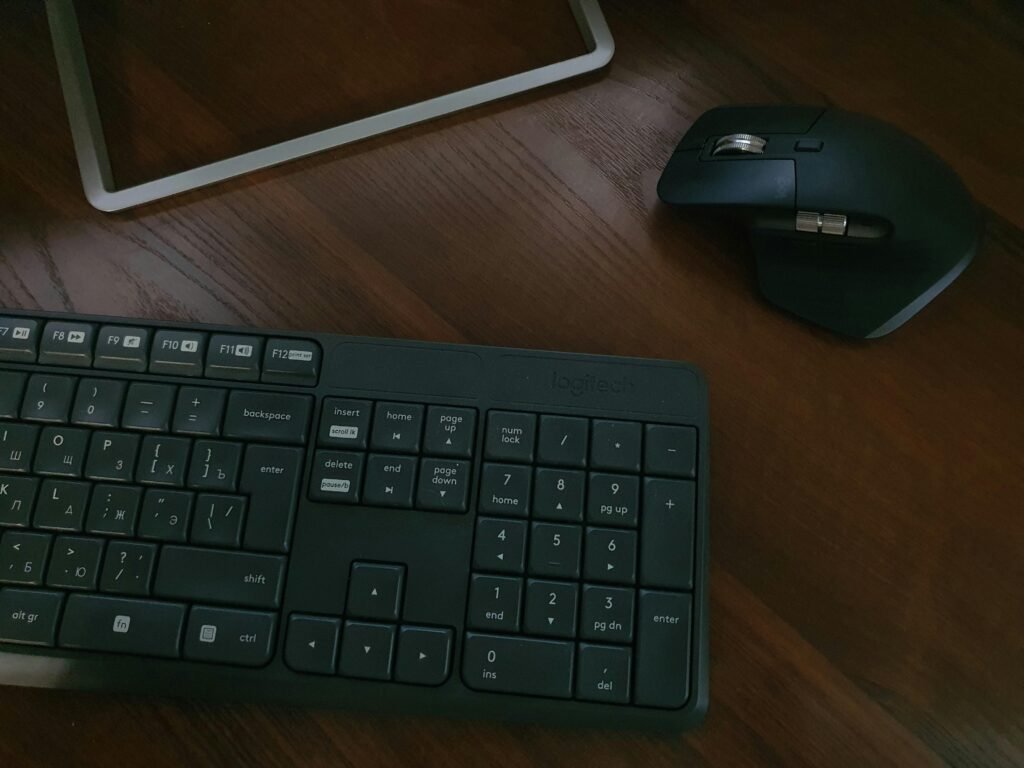 Schwarze Computertastatur liegt neben einem weißen iPad auf einer Schreibtischoberfläche, moderner Arbeitsplatz