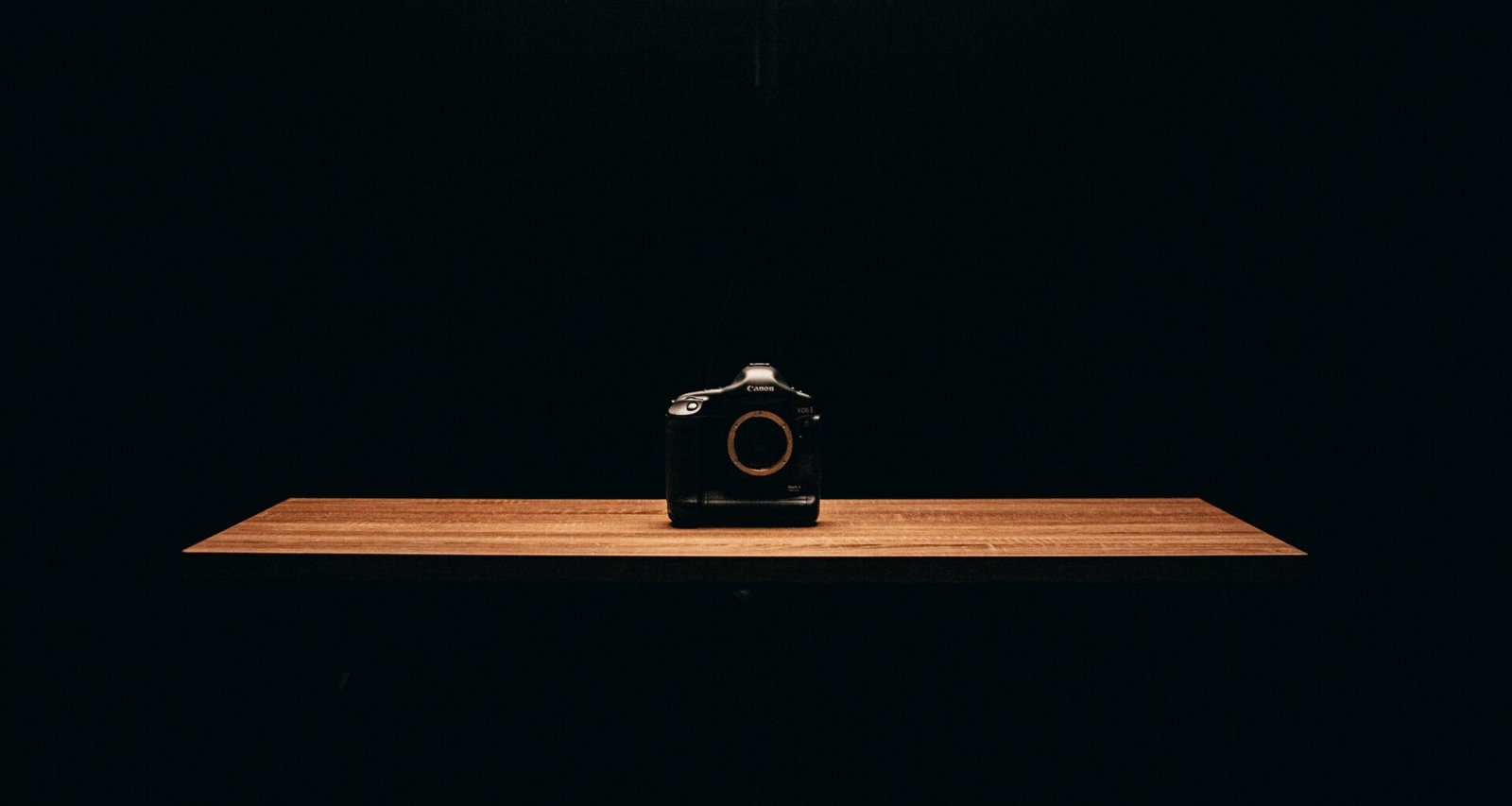 Schwarze Kompaktkamera auf einem braunen Holztisch, aufgenommen im Nahbereich, zeigt das klassische Kameradesign.