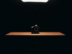 Schwarze Kompaktkamera auf einem braunen Holztisch, aufgenommen im Nahbereich, zeigt das klassische Kameradesign.