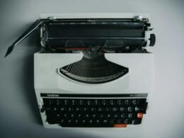 Schwarze Schreibmaschine mit eingespannter Seite in Nahaufnahme auf einem Tisch