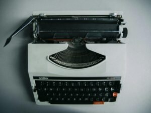 Schwarze Schreibmaschine mit eingespannter Seite in Nahaufnahme auf einem Tisch