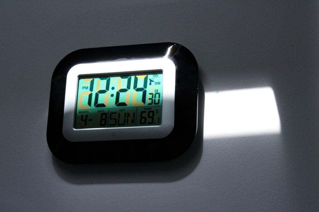 Schwarze und graue digitale Wanduhr mit gut lesbarem LED-Display auf einer neutralen Wand