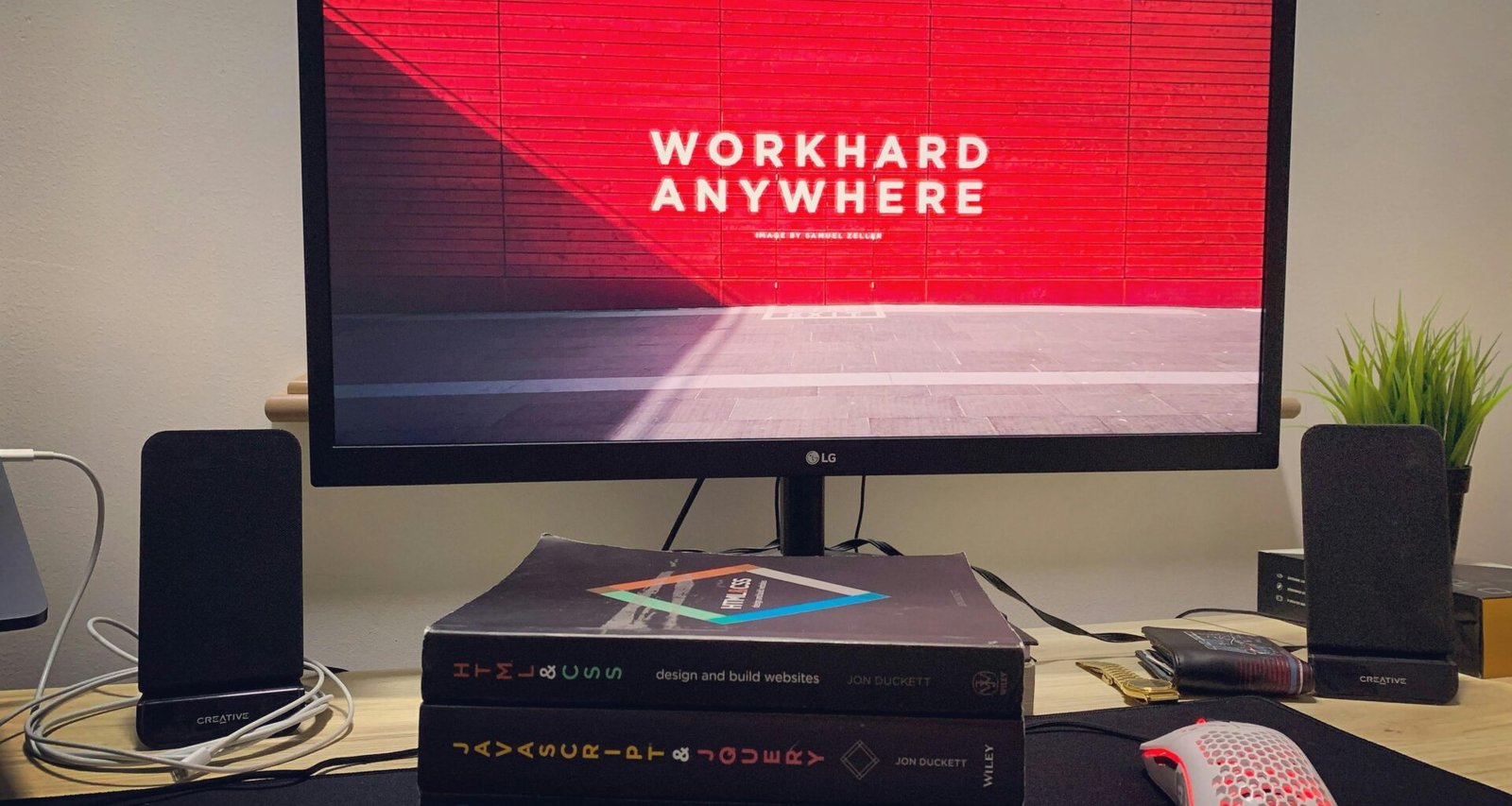 Schwarzer Flachbildfernseher eingeschaltet auf hellem Untergrund, daneben eine weiße Fernbedienung mit Technik-Fokus