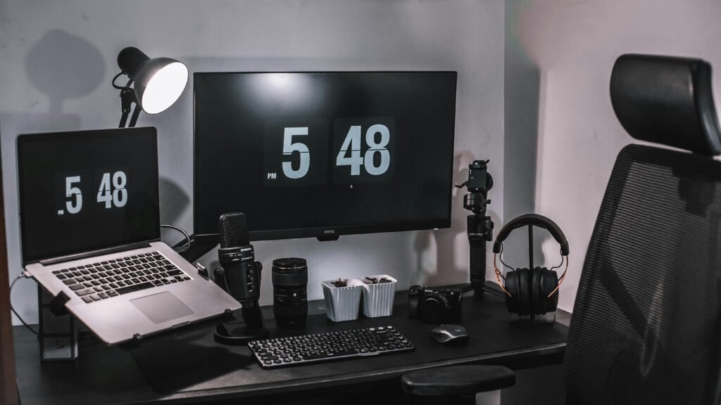 Ein schwarzer Flachbildschirm-Computer steht auf einem schwarzen Holztisch in einer modernen Büroumgebung.