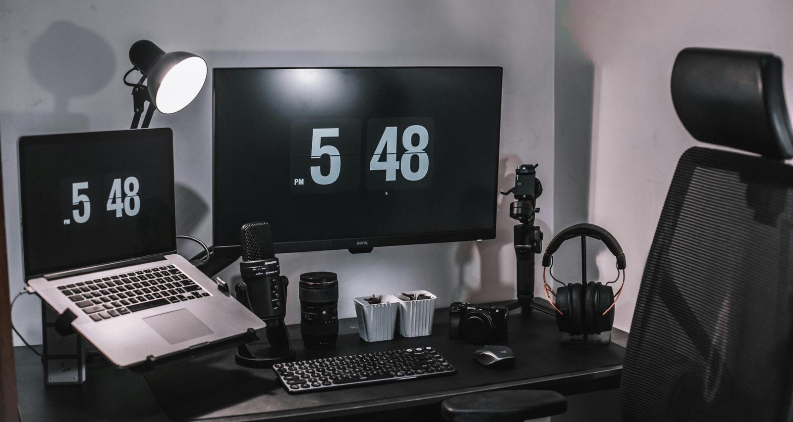Ein schwarzer Flachbildschirm-Computer steht auf einem schwarzen Holztisch in einer modernen Büroumgebung.