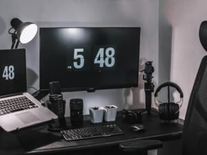 Ein schwarzer Flachbildschirm-Computer steht auf einem schwarzen Holztisch in einer modernen Büroumgebung.