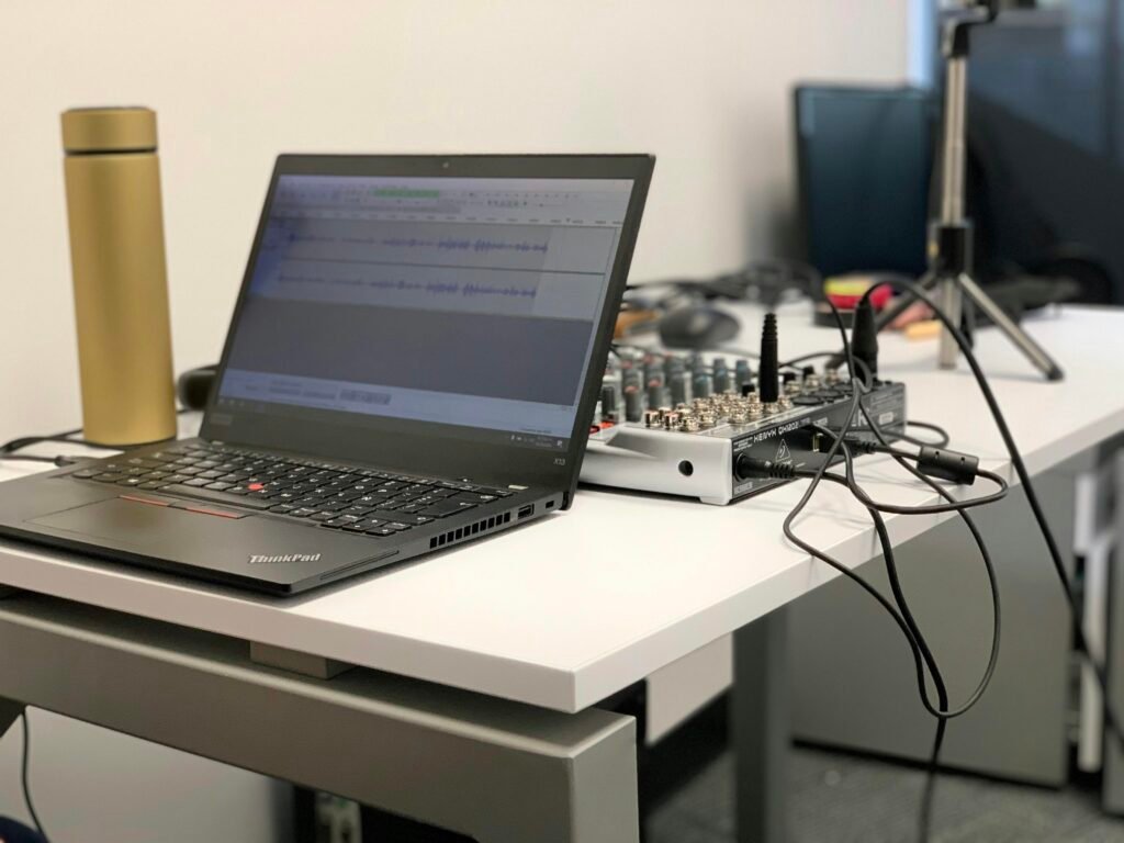 Schwarzes Laptop auf einem weißen Tisch, fotografiert aus der Seitenansicht mit klarem Fokus auf die Technik.