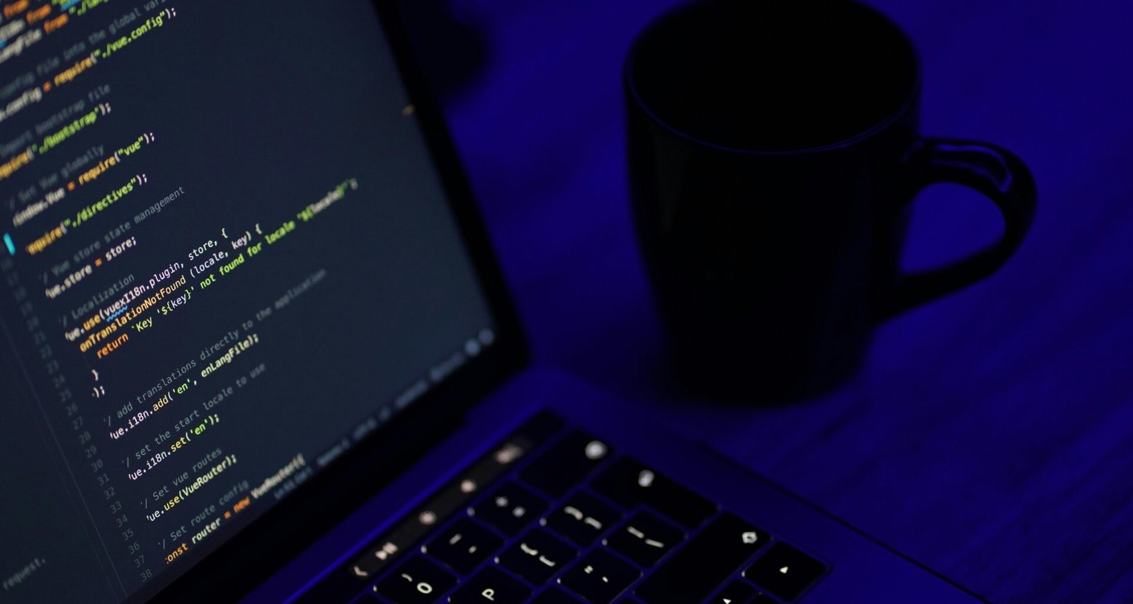 Schwarzes aufgeklapptes Laptop neben einer schwarzen Keramiktasse auf einem Arbeitstisch, ideal für Homeoffice oder Online-Arbeit.
