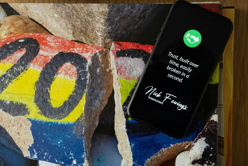 Schwarzes iPhone 5 auf blau-gelb-rot gemustertem Felsen, fotografiert von oben, geeignet für Tech- und Marketingartikel