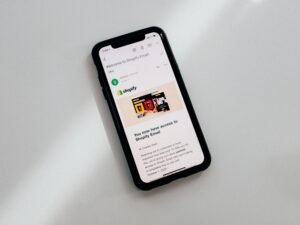 Schwarzes iPhone 5 auf einer weißen Tischoberfläche mit deutlichem Fokus auf das Gerät und klare Linienstruktur.