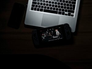 Schwarzes iPhone 7 liegt auf Tisch neben einem geöffneten MacBook Pro, beide Geräte im Workspace platziert.