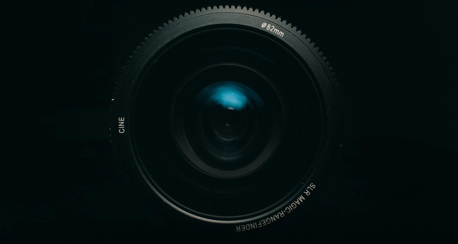 Schwarzes Kameraobjektiv auf weißem Untergrund, formatfüllend und detailreich fotografiert, geeignet für Technikartikel