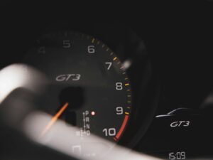 Schwarzes Armaturenbrett mit beleuchtetem Tachometer und digitalen Anzeigen eines modernen Autos aus der Nahsicht