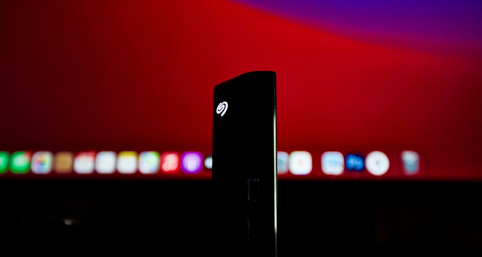 Schwarzes, rechteckiges technisches Gerät platziert auf einer roten Oberfläche im minimalistischen Stil, Nahaufnahme