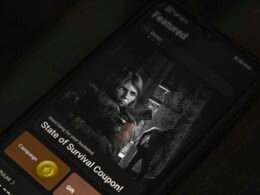 Ein schwarzes Smartphone mit dem Bild eines Mannes im schwarzen Hemd auf dem Display, neutraler Hintergrund.