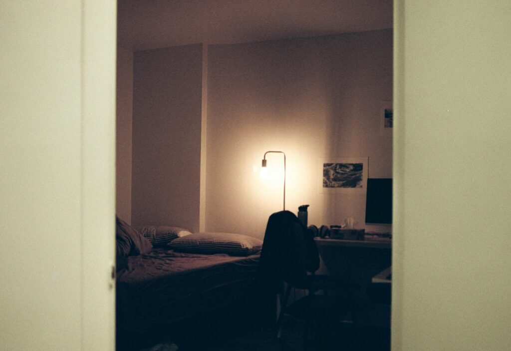 Schwarzer Textilstoff auf einem Bett in einem minimalistischen Schlafzimmer mit weißer Wand im Hintergrund