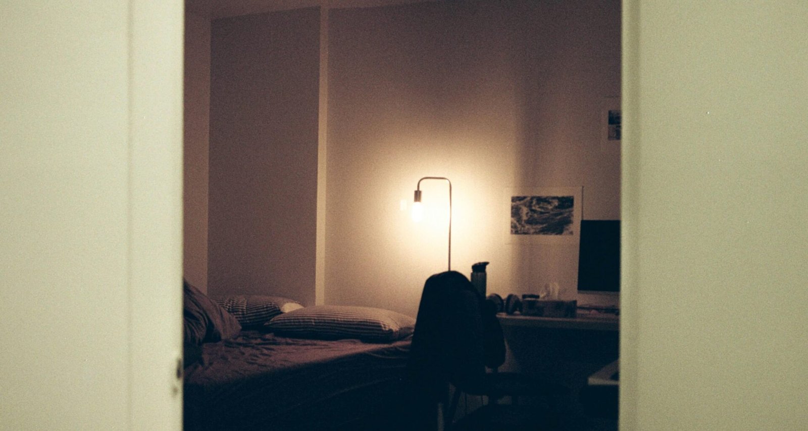 Schwarzer Textilstoff auf einem Bett in einem minimalistischen Schlafzimmer mit weißer Wand im Hintergrund