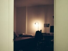 Schwarzer Textilstoff auf einem Bett in einem minimalistischen Schlafzimmer mit weißer Wand im Hintergrund