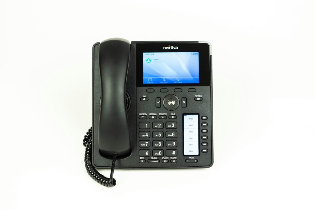 Schwarzes und graues IP-Tischtelefon auf einem modernen Büroarbeitsplatz mit Fokus auf digitale Kommunikationstechnologie
