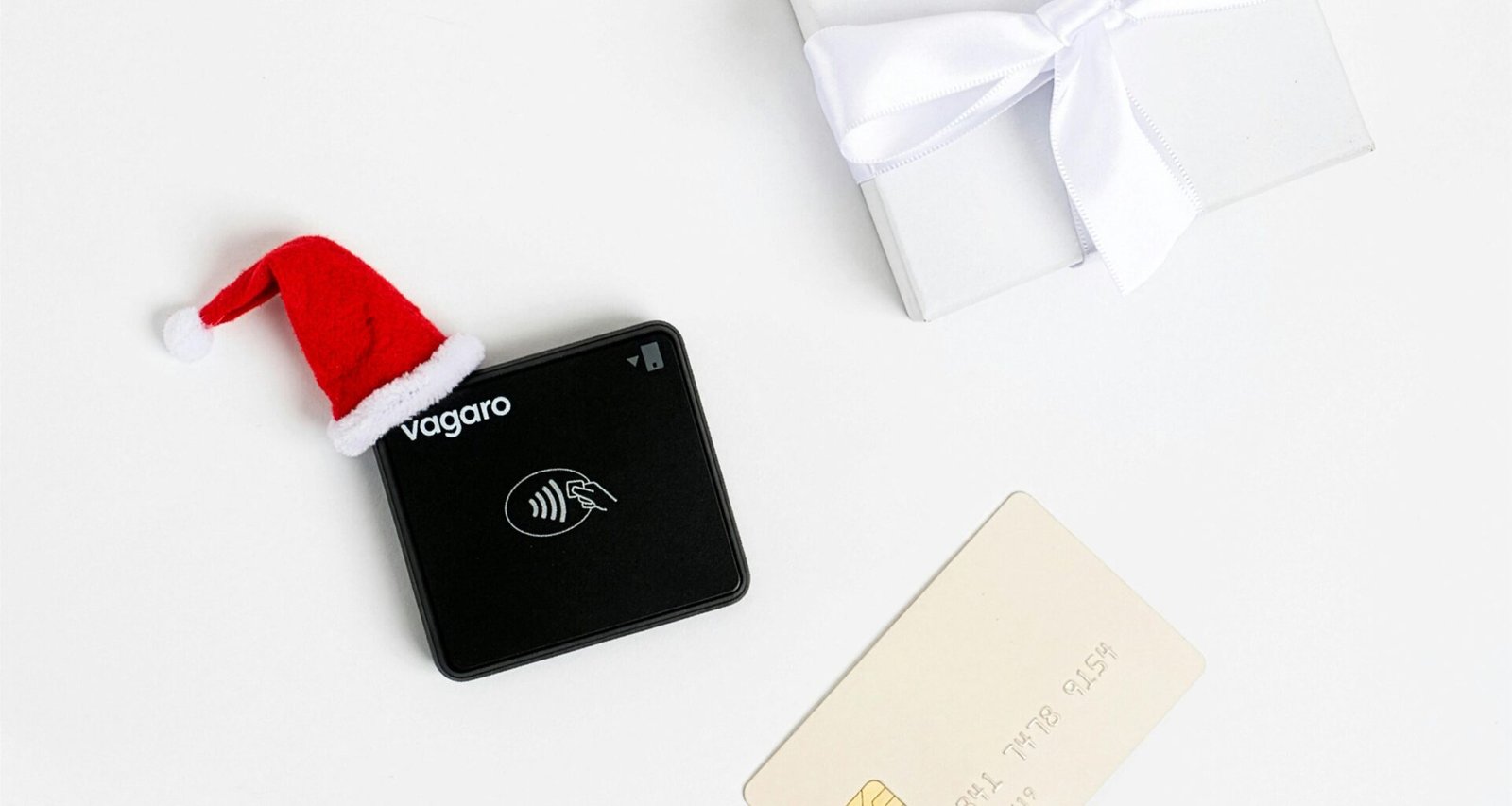 Schwarzes Zahlungsterminal mit Weihnachtsmütze und Geschenk, Symbol für festliche digitale Zahlungen im Handel