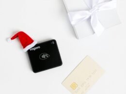 Schwarzes Zahlungsterminal mit Weihnachtsmütze und Geschenk, Symbol für festliche digitale Zahlungen im Handel