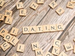 Holztisch mit Scrabble-Buchstaben, die das Wort Dating bilden; Fokus auf digitale Partnersuche