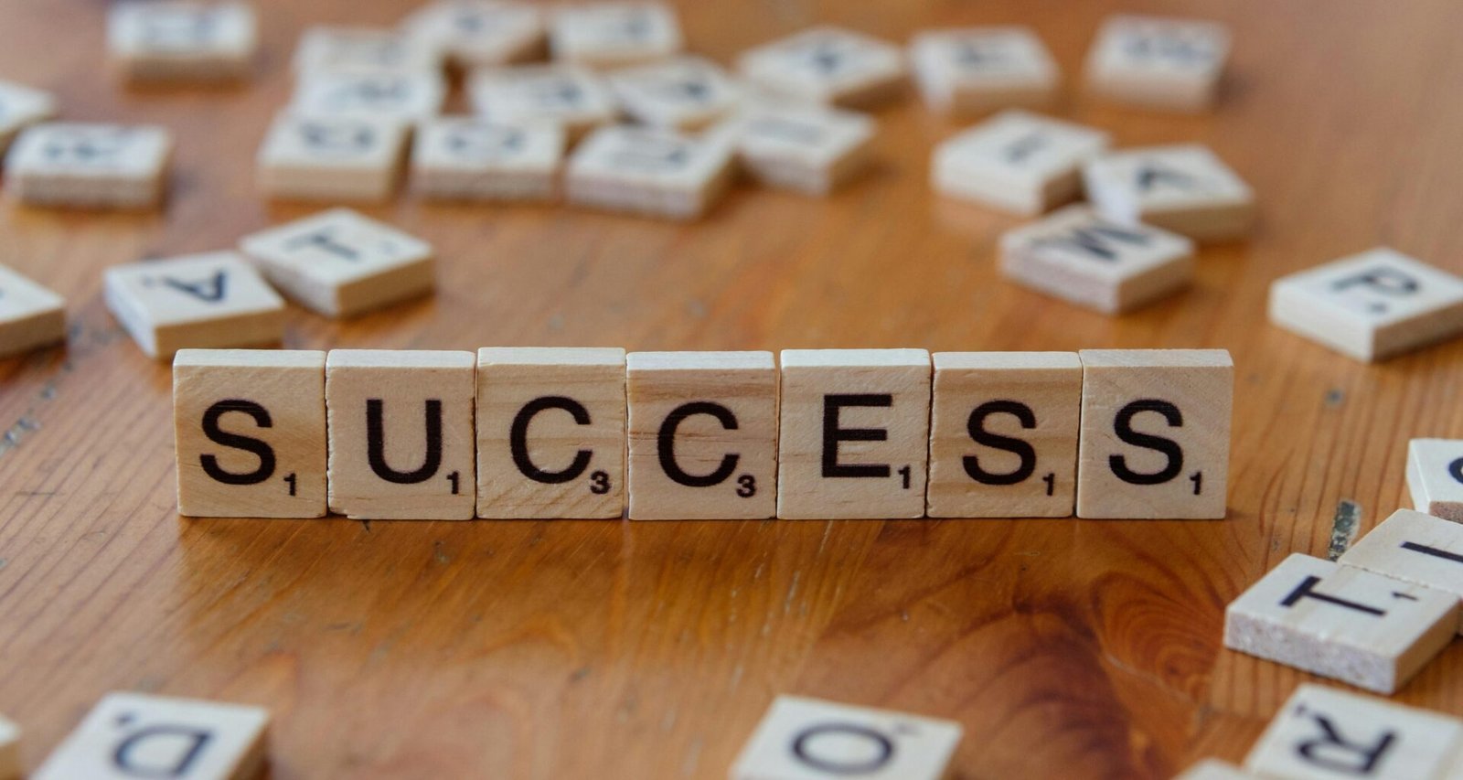 Scrabble-Spielsteine, die das Wort Success formen, arrangiert auf einer hölzernen Tischoberfläche