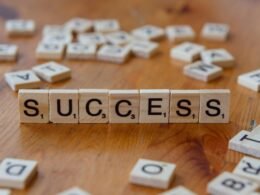 Scrabble-Spielsteine, die das Wort Success formen, arrangiert auf einer hölzernen Tischoberfläche