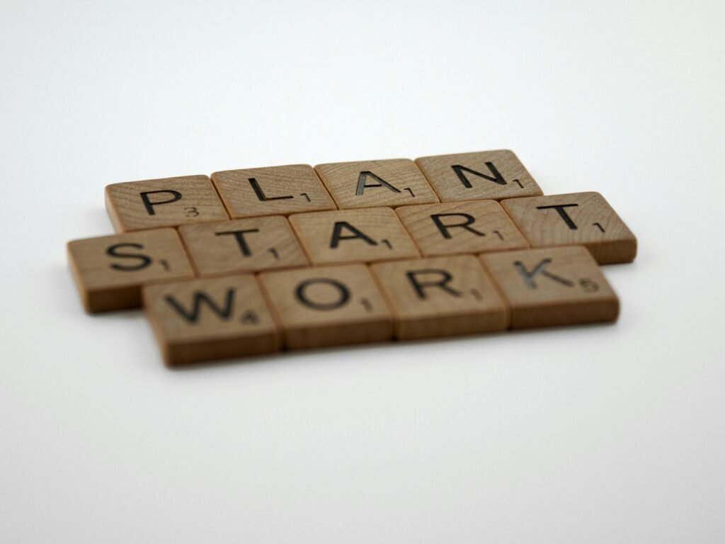 Scrabble-Steine bilden die Wörter Plan, Start und Work auf einem Tisch als Symbol für Geschäftsplanung und Strategie