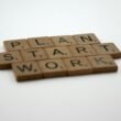 Scrabble-Steine bilden die Wörter Plan, Start und Work auf einem Tisch als Symbol für Geschäftsplanung und Strategie