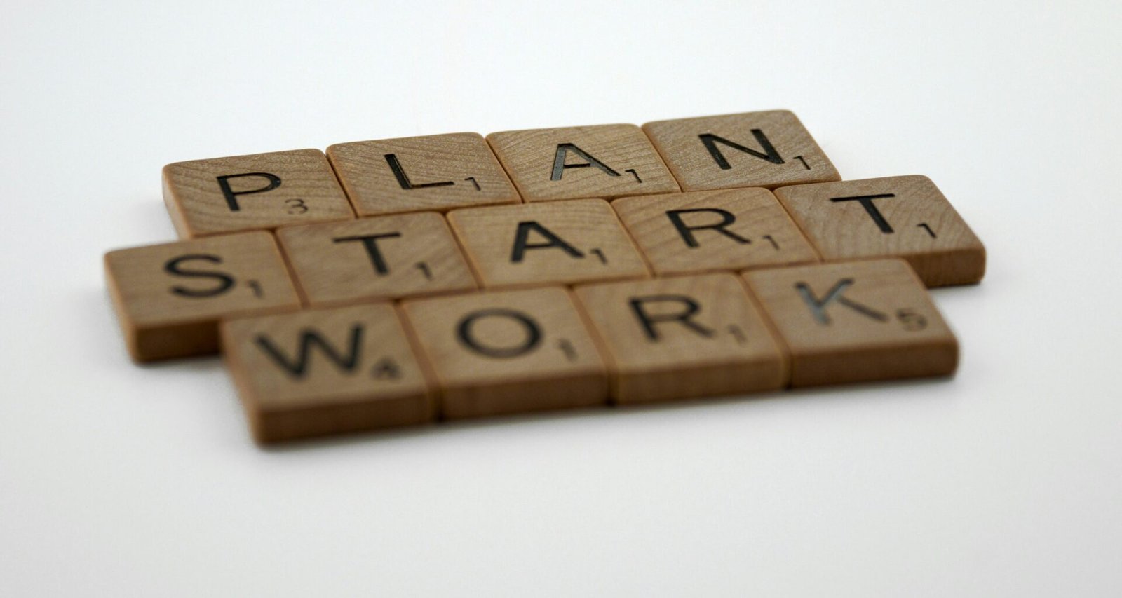 Scrabble-Steine bilden die Wörter Plan, Start und Work auf einem Tisch als Symbol für Geschäftsplanung und Strategie