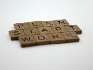 Scrabble-Steine bilden die Wörter Plan, Start und Work auf einem Tisch als Symbol für Geschäftsplanung und Strategie