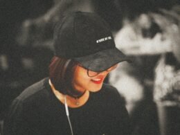 Selektive Farbfotografie einer Frau mit schwarzer, eng anliegender Kappe im modernen Ambiente