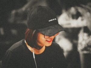 Selektive Farbfotografie einer Frau mit schwarzer, eng anliegender Kappe im modernen Ambiente