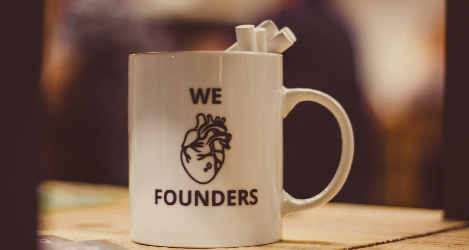 Selektiver Fokus auf eine weiße Keramiktasse mit Herzmotiv und Aufschrift Founders, auf einem Tisch platziert