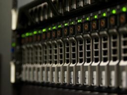 Server-Rack mit mehreren Hardwarekomponenten und grün blinkenden LEDs in einem professionellen Rechenzentrum.