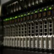 Nahaufnahme eines Server-Racks mit blinkenden grünen Lichtern, die aktive Netzwerk- und Systemkomponenten anzeigen