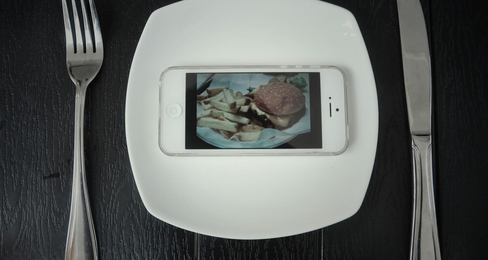 Silbernes iPhone 5 von oben liegend fotografiert, Fokus auf die klaren Linien und das kompakte Smartphone-Design.