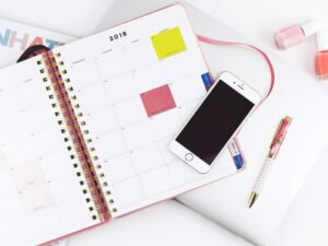 Silbernes iPhone 6, platziert auf einem weißen Spiralnotizbuch, aus der Vogelperspektive aufgenommen, klare Linien und Kontraste.