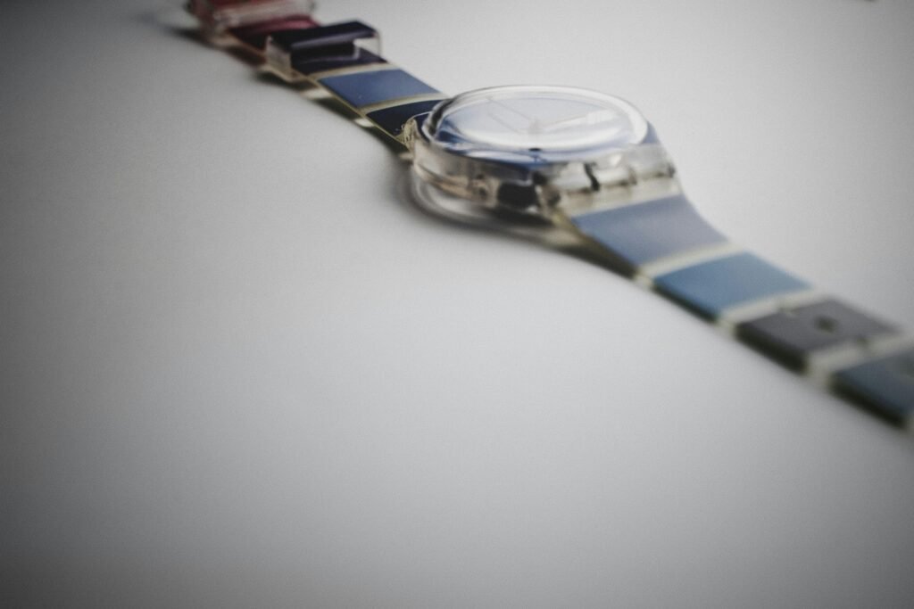 Silberne und blaue runde Analog-Armbanduhr, die auf einer dunklen Oberfläche liegt, gut sichtbar im Vordergrund