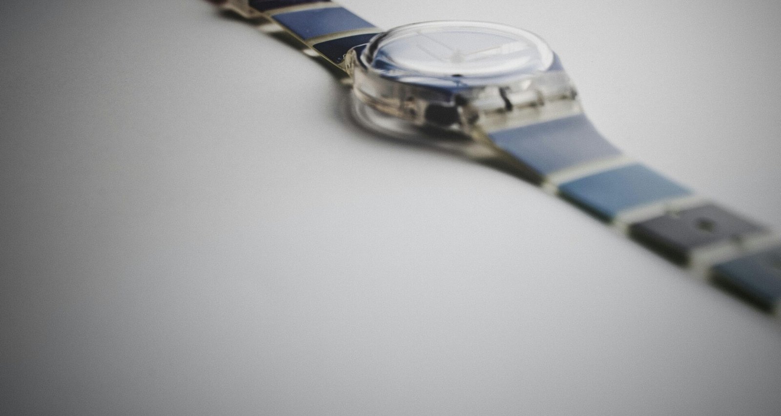 Silberne und blaue runde Analog-Armbanduhr, die auf einer dunklen Oberfläche liegt, gut sichtbar im Vordergrund