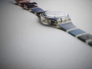 Silberne und blaue runde Analog-Armbanduhr, die auf einer dunklen Oberfläche liegt, gut sichtbar im Vordergrund