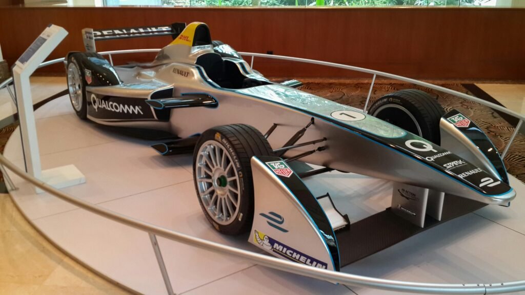 Silberner Formel-E-Rennwagen steht ausgestellt auf einer Motorsportveranstaltung, Elektroauto im Fokus.